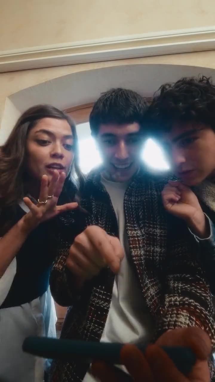 Tres jóvenes iluminados por la pantalla del celular mientras ven el partido
