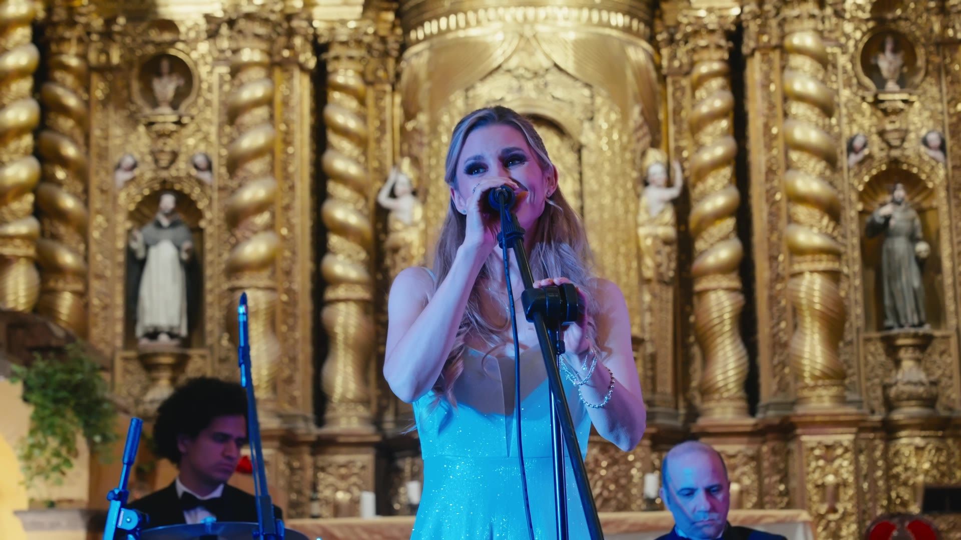 Cantante con vestido azul frente al retablo