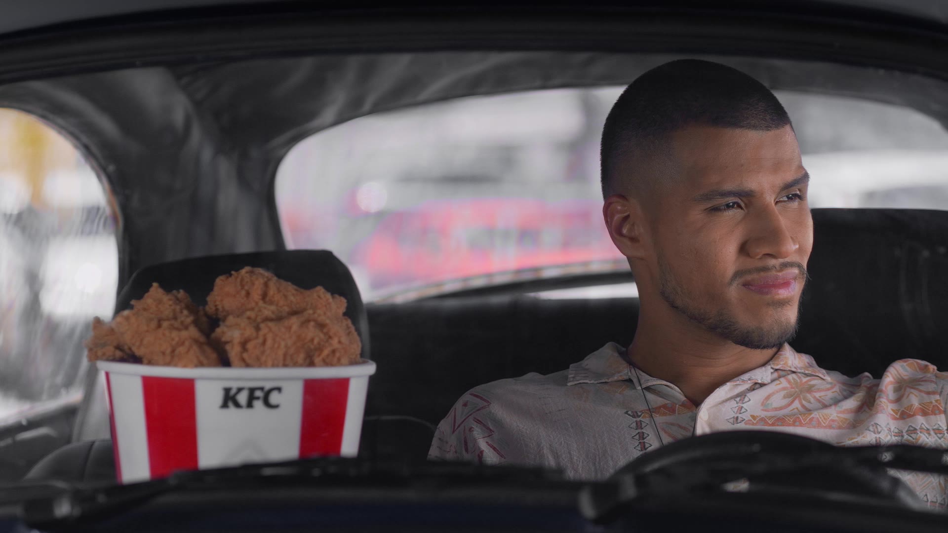 Escena del comercial: un hombre en su auto con un bucket de KFC