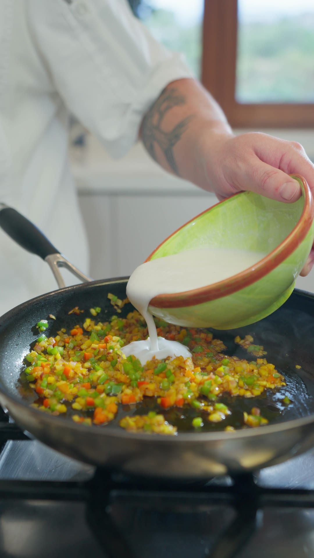 Leche de coco cayendo sobre el sofrito en la sartén