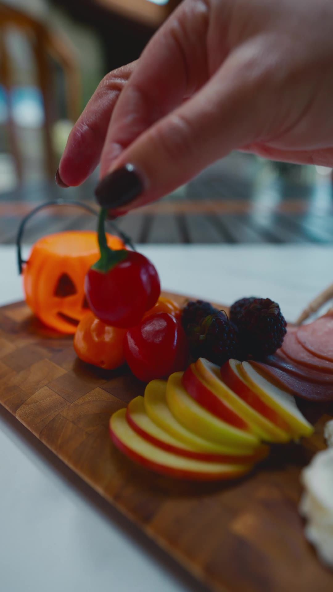 Mano colocando un tomate cherry en la tabla