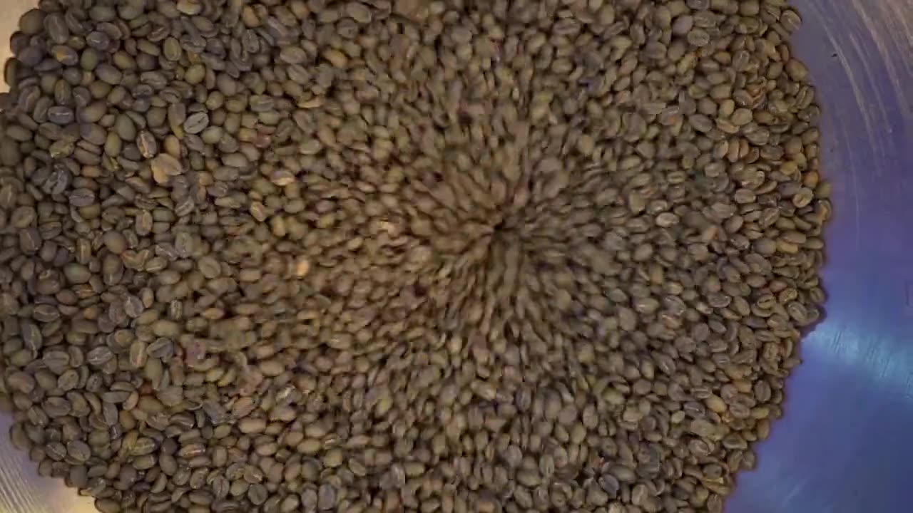 Granos de café verde en el tostador